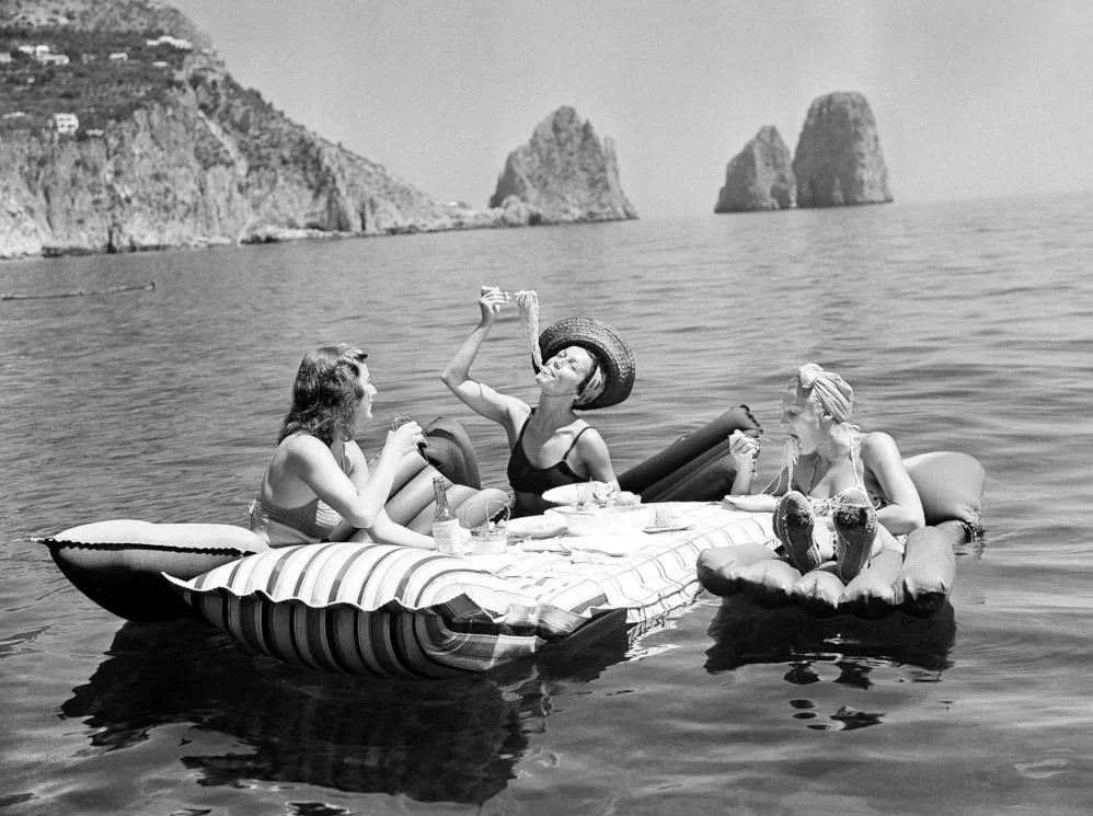 Drei Damen auf Kolma-Luftmatratzen vor den Faraglioni von Capri, ca. 1955